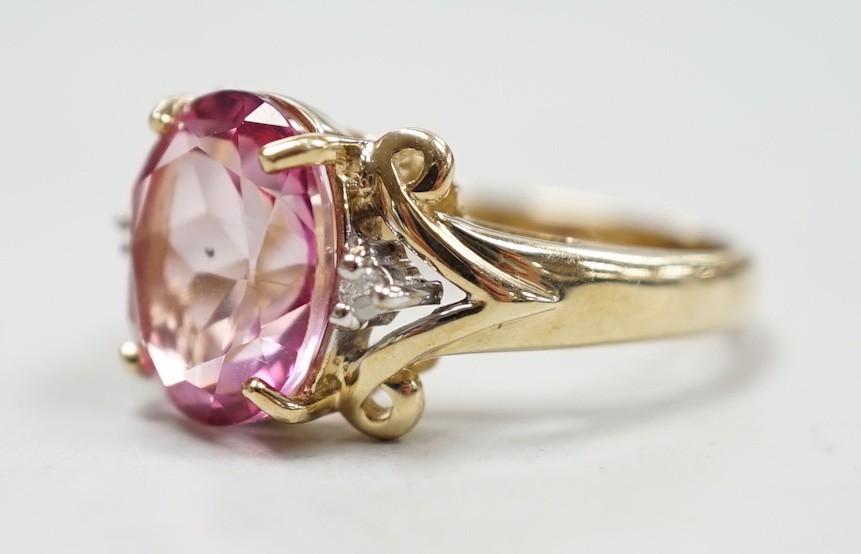 A modern 9ct gold and single stone oval cut flamingo topaz dress ring with two stone diamond set shoulders, size N, gross weight 5.3 grams, with Gems TV certificate.